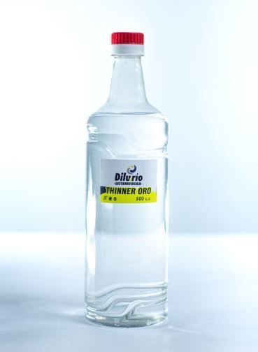 Botella de vidrio transparente con tapón rojo; contiene un líquido transparente.