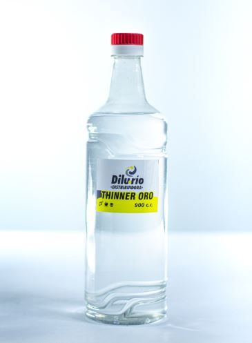 Botella de vidrio transparente de disolvente de pintura con tapa roja, etiquetada 