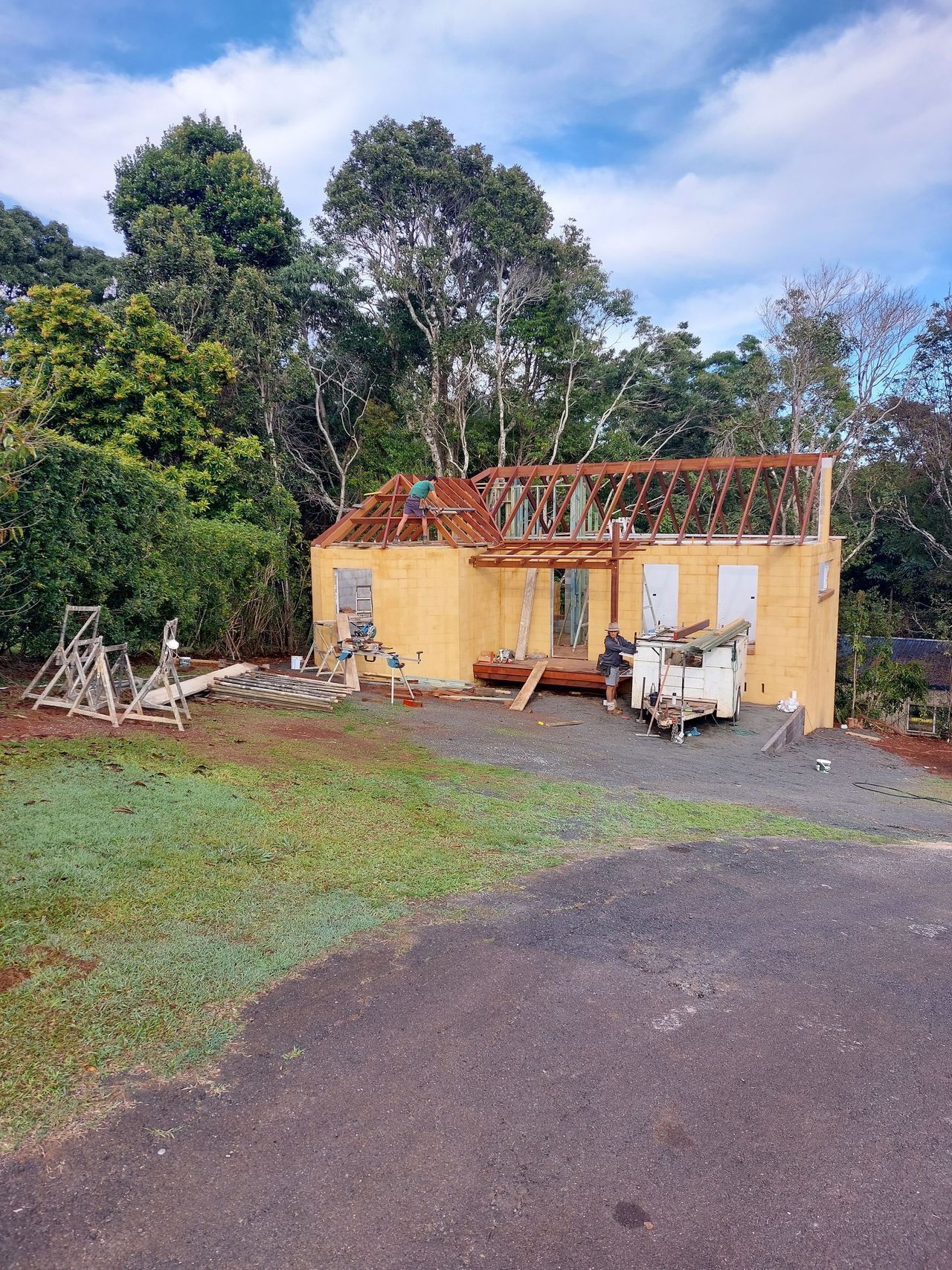A yellow house is being built with a red roof.