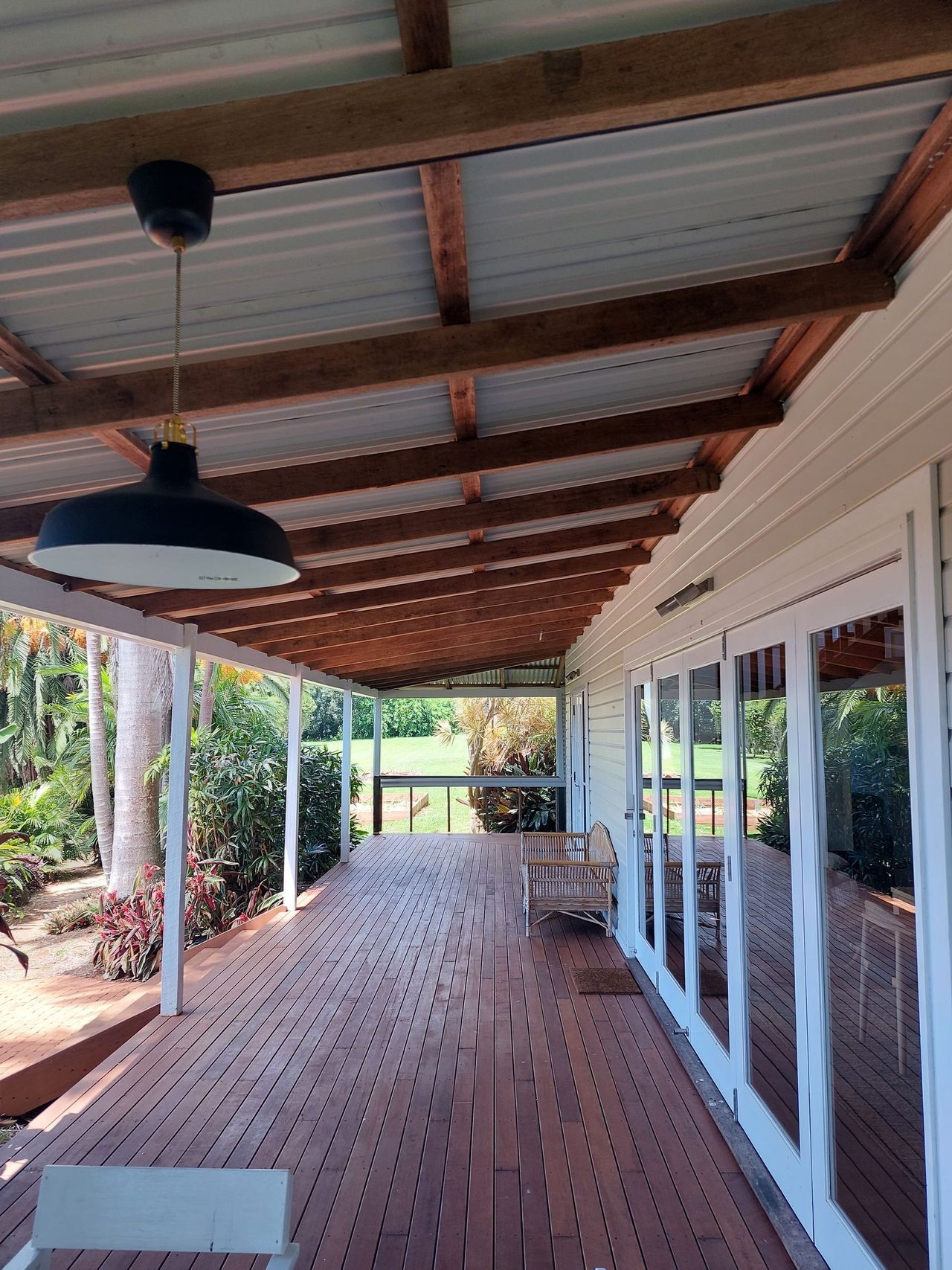 A wooden deck with a ceiling fan and lots of windows