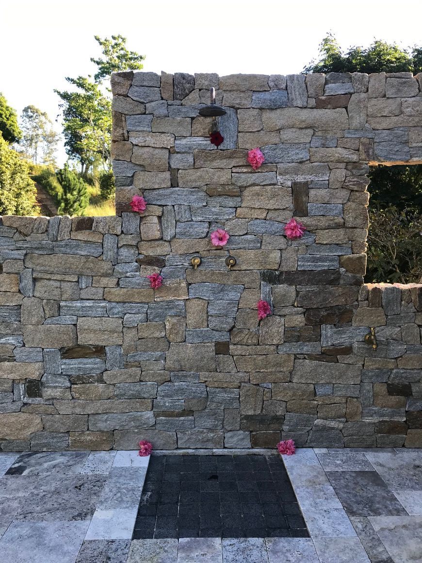 A stone wall with pink flowers hanging from it