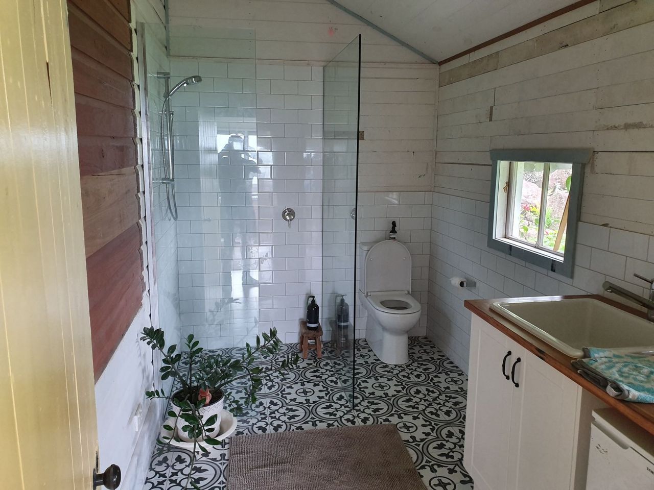 A bathroom with a toilet , sink and shower.