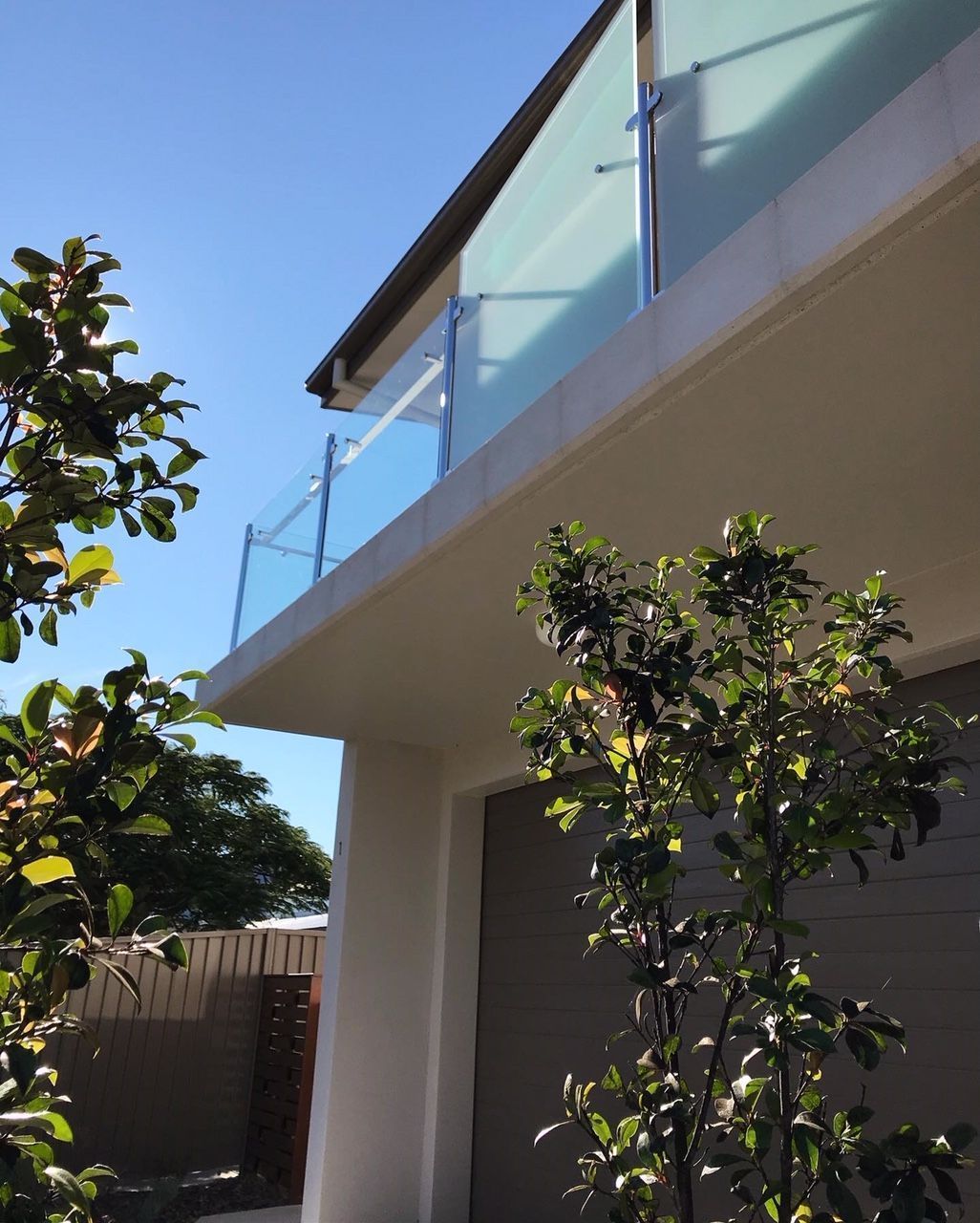 A house with a balcony and a tree in front of it