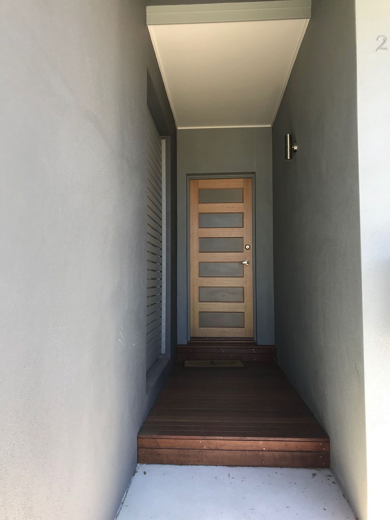 A hallway with a wooden door and the number 2 on the wall