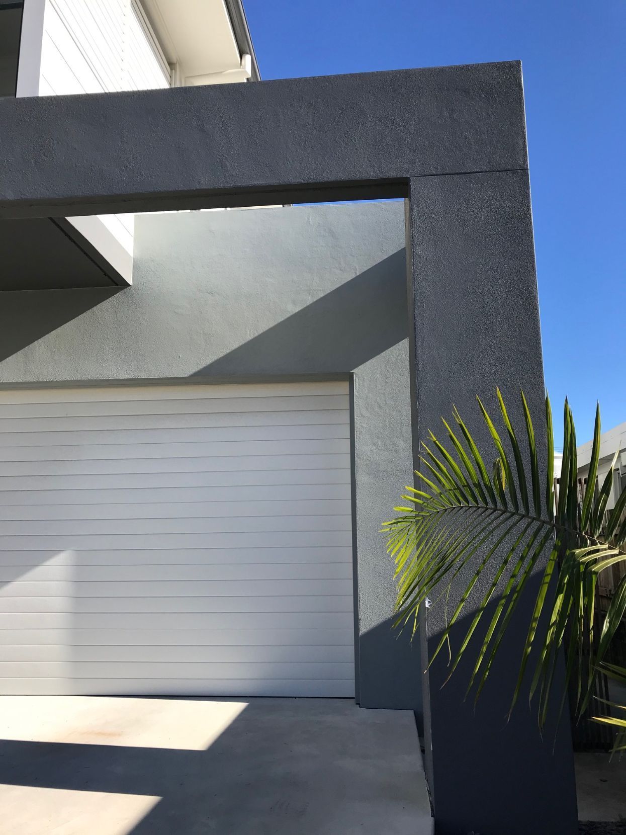 A white garage door is sitting in front of a house.