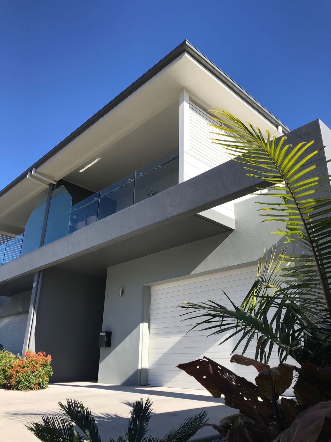 A large house with a balcony and a palm tree in front of it