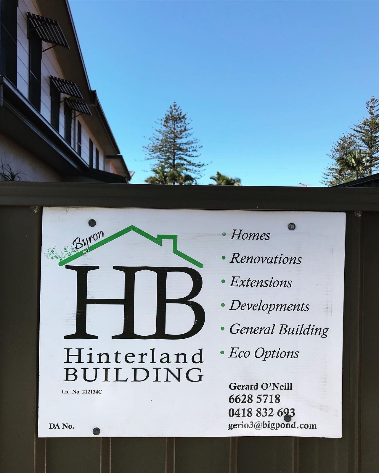 A sign for hinterland building hangs on a fence