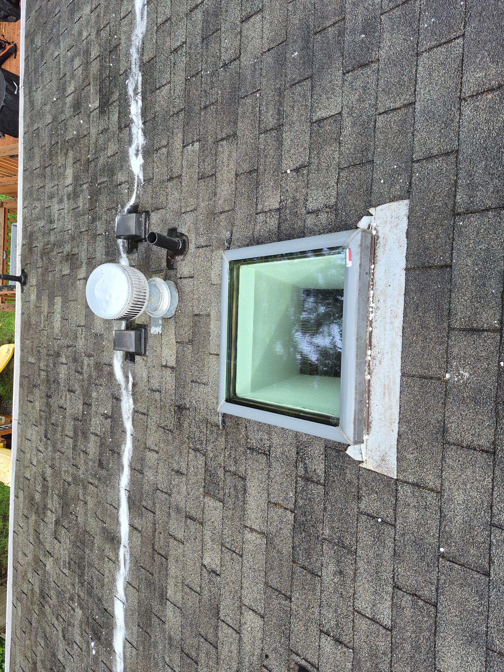 Exterior wall with white utility meter and a small square window with green glass the side of a building.