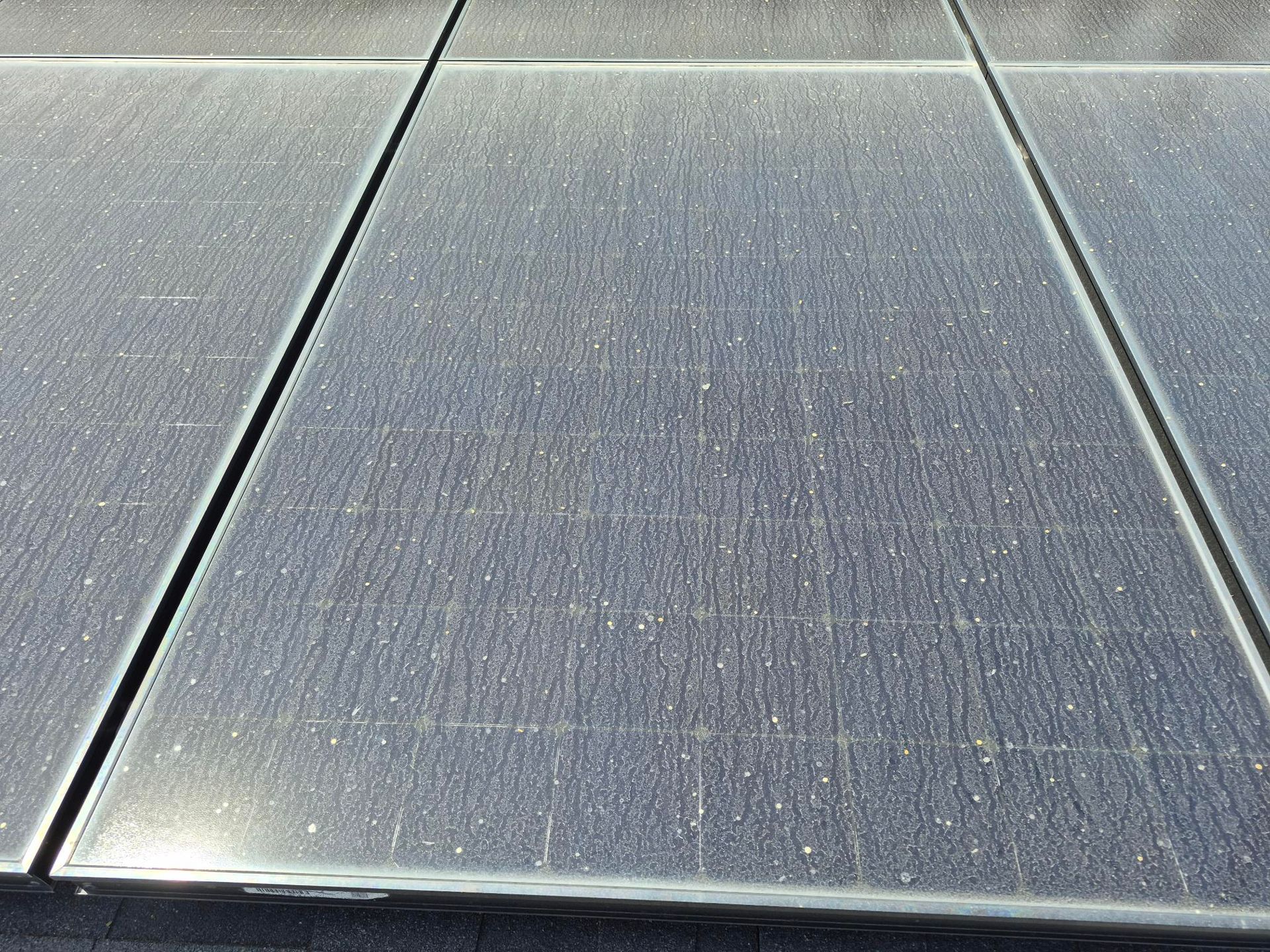 Close-up of gray solar panels with metallic seams and speckled surface texture.