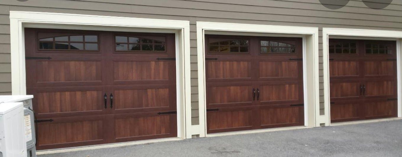 Three brown garage doors are sitting next to each other on the side of a house.