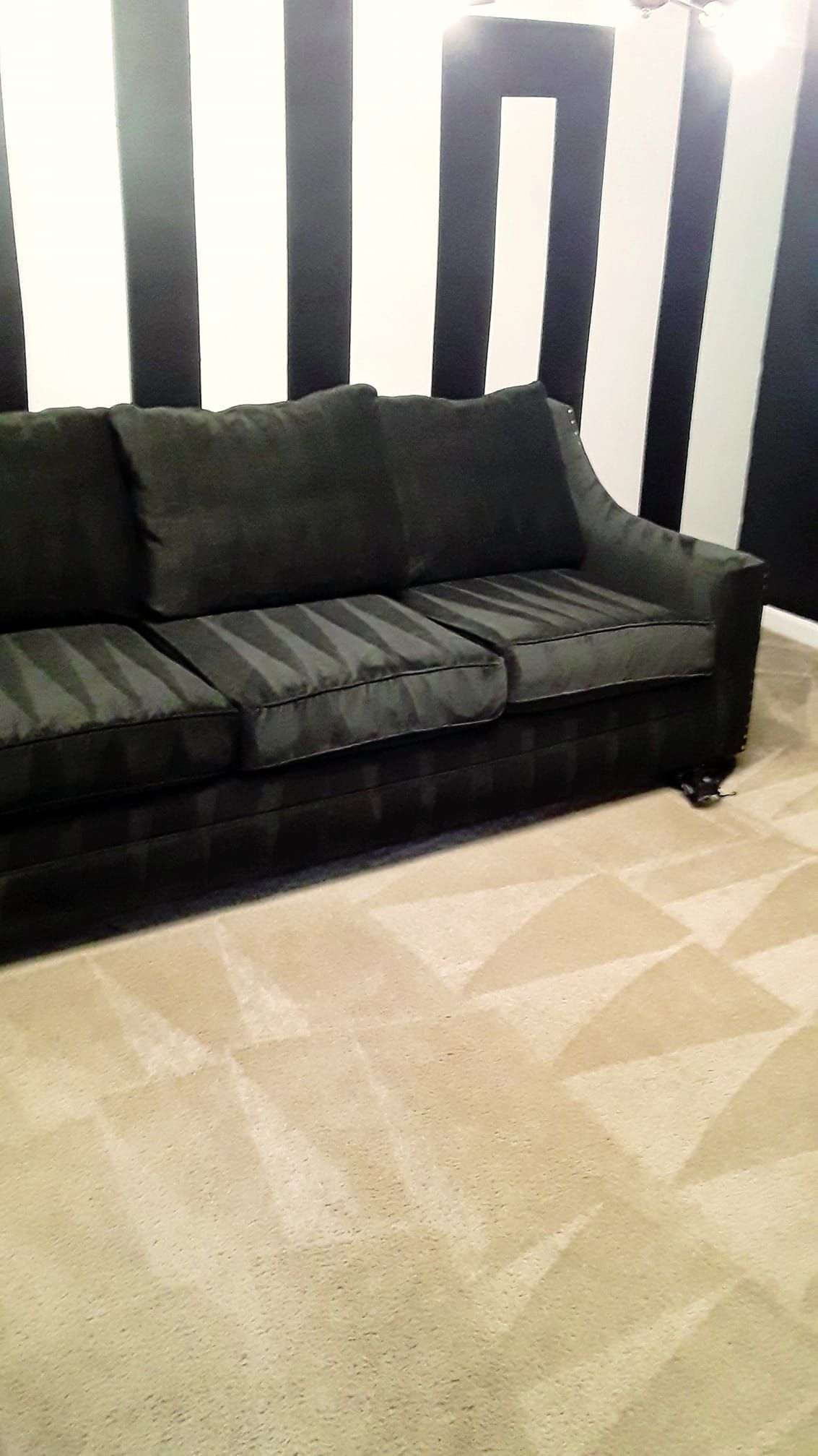 a black couch in front of a black and white striped wall
