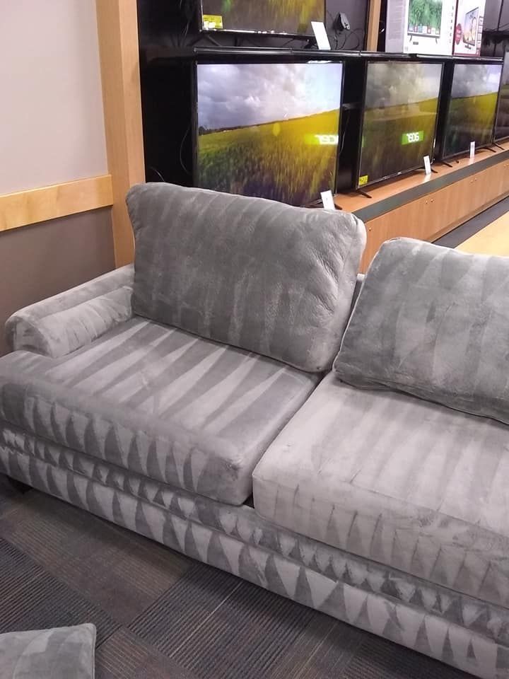a gray couch in front of a display of toshiba tvs