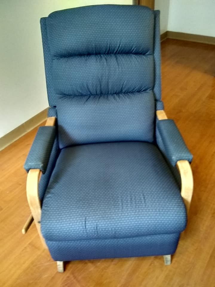 a blue recliner is sitting on a wooden floor