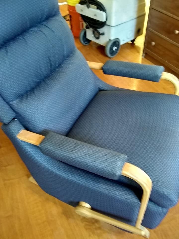 a blue chair sits on a wooden floor next to a vacuum cleaner