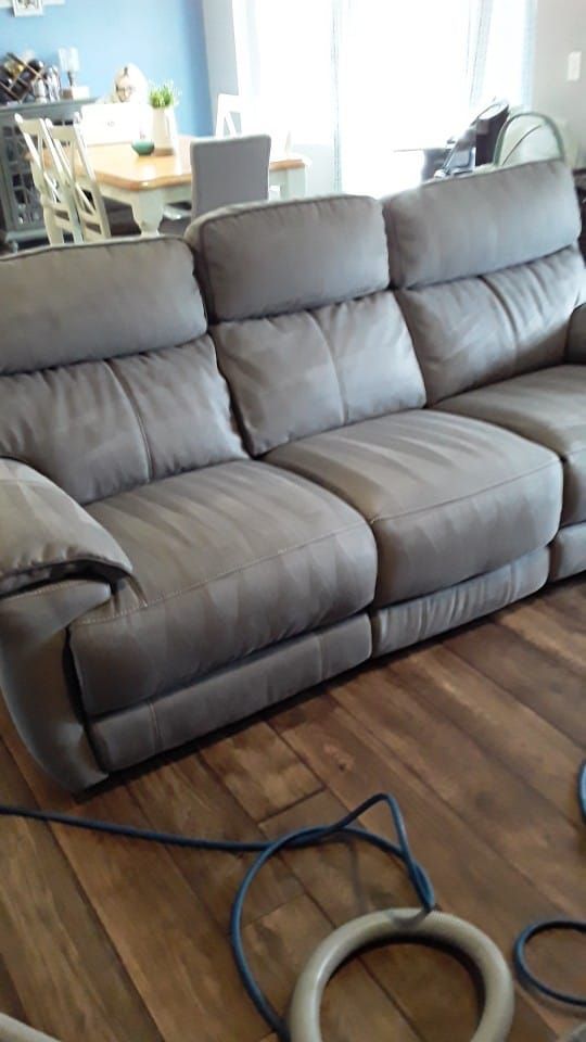 a grey leather couch is sitting on a wooden floor