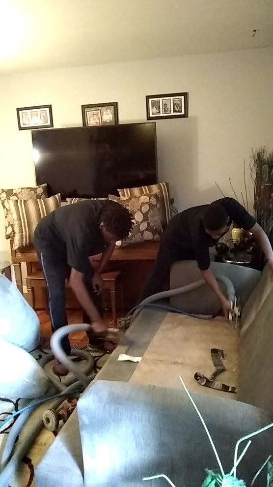 two men are working on a couch in a living room