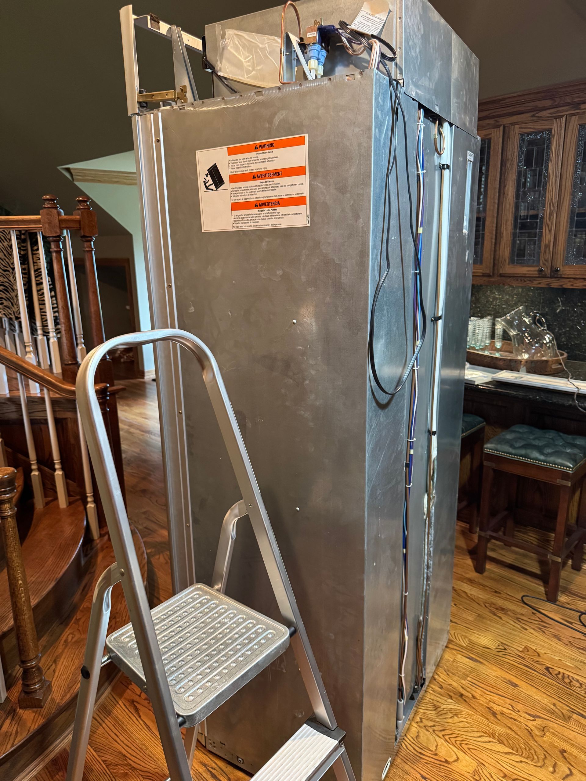Large metallic air conditioning unit next to a stepladder in a home interior.