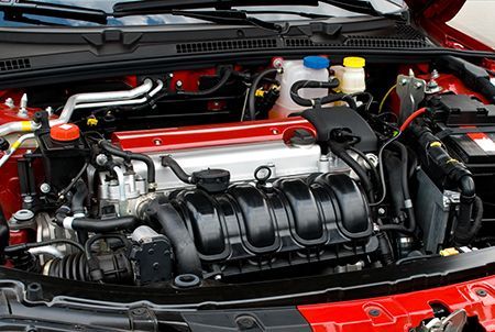 Open car engine bay with black intake manifold and red body panels