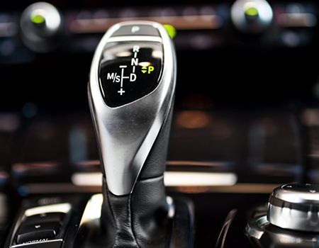 Close-up of a car’s automatic gear shift with illuminated shift indicators.