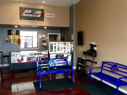 Blue-and-red sports-themed waiting area with chairs, counter, and TV in a small shop
