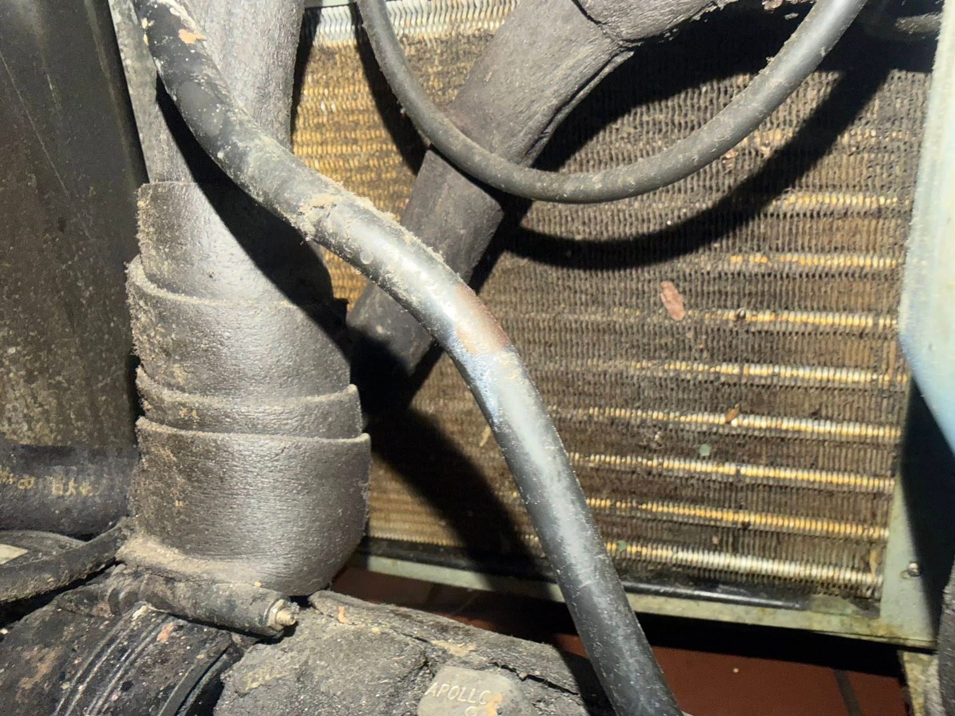 Dusty HVAC coil and wiring close-up behind a metal grille