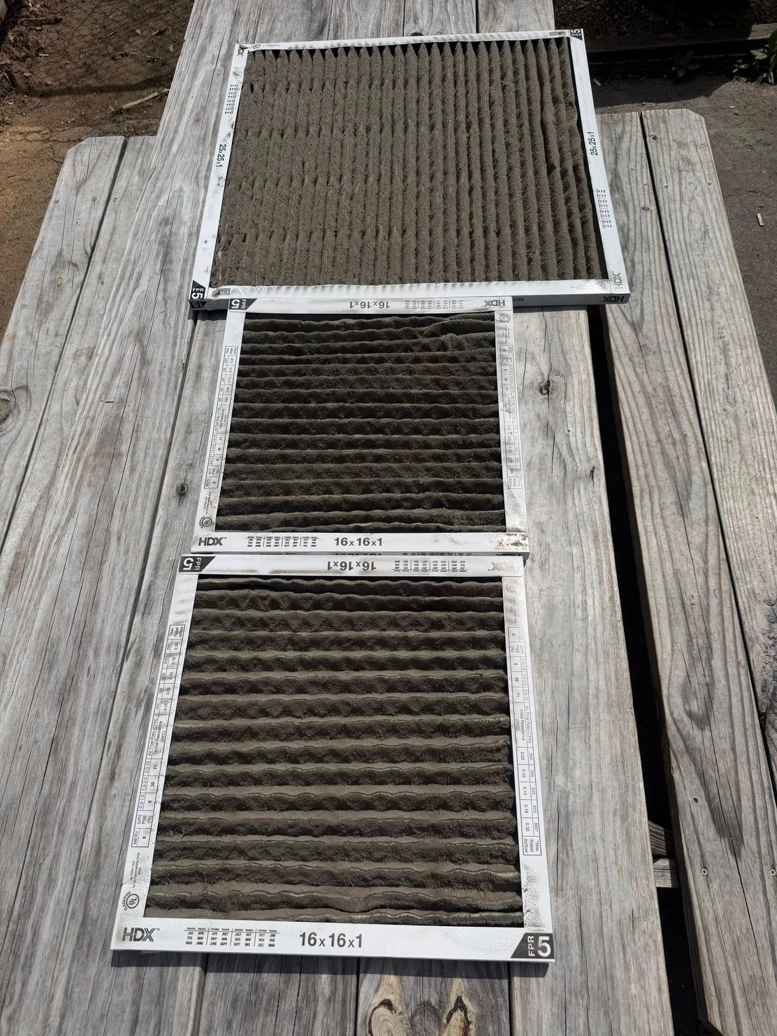 Three rectangular metal-framed mesh panels leaning on wooden pallets in a warehouse.