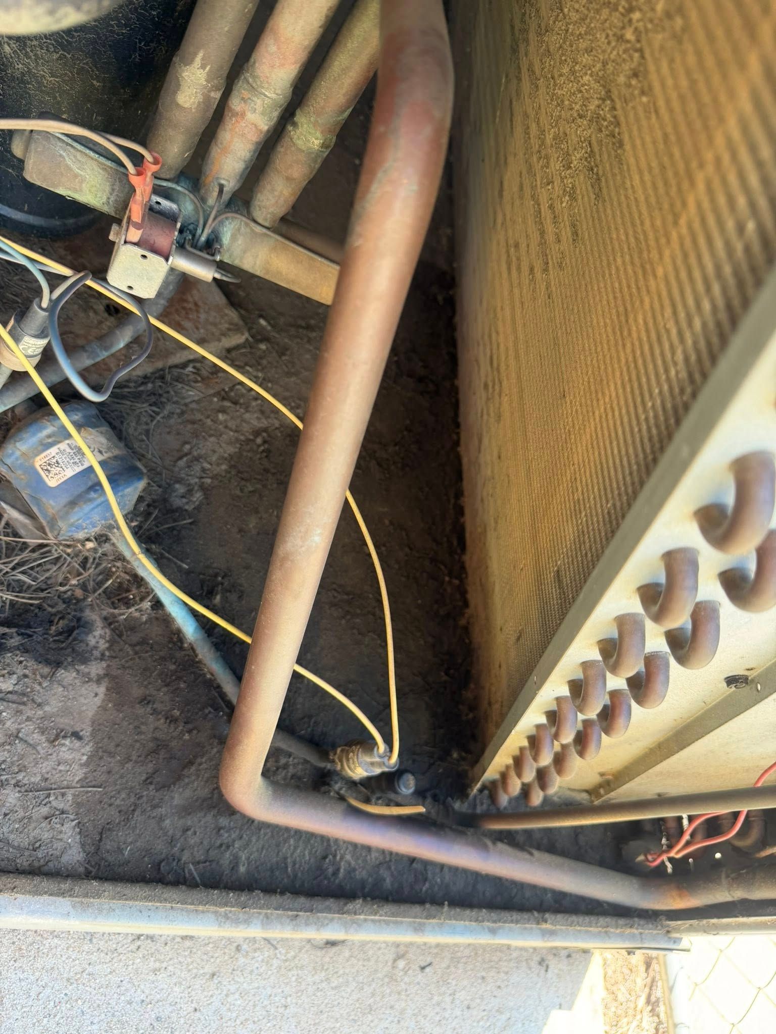 HVAC unit with copper pipes, wiring, and dusty coils in a mechanical area