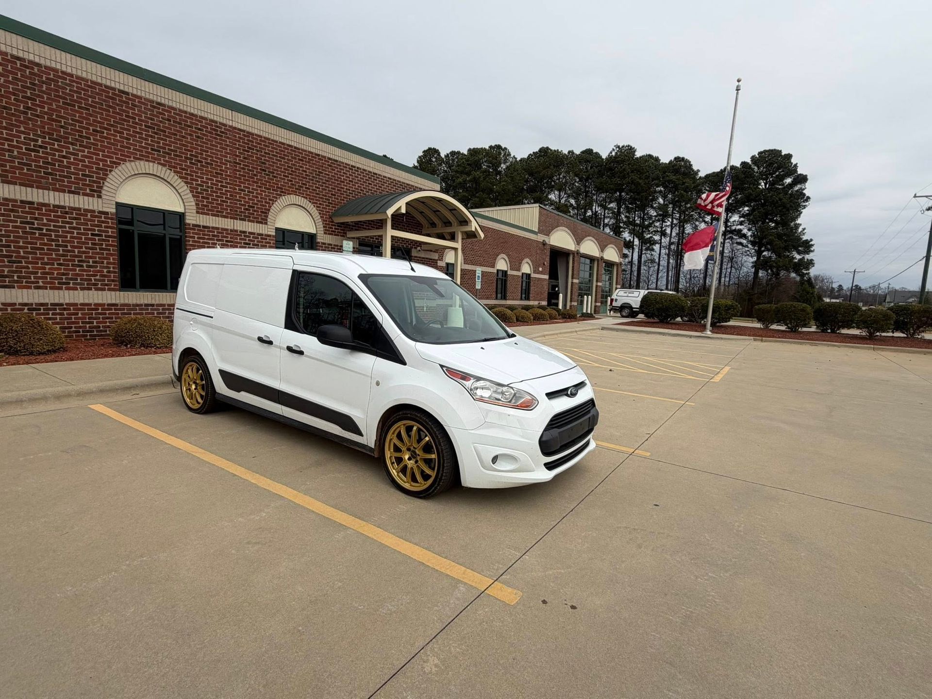 White cargo van parked in front of a brick building in a mostly empty parking lot