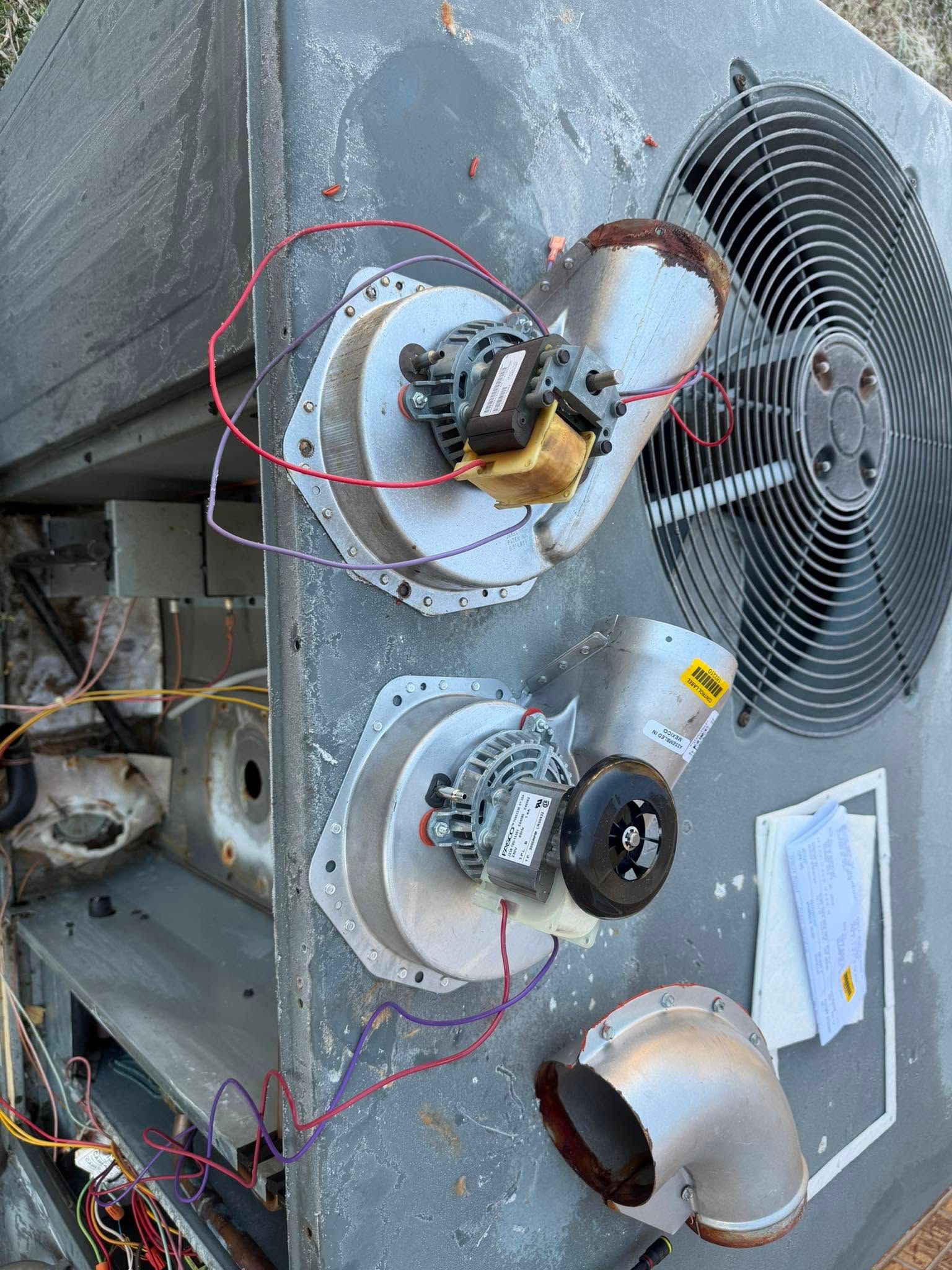 Damaged HVAC unit with exposed wiring and three broken fan assemblies on a metal panel