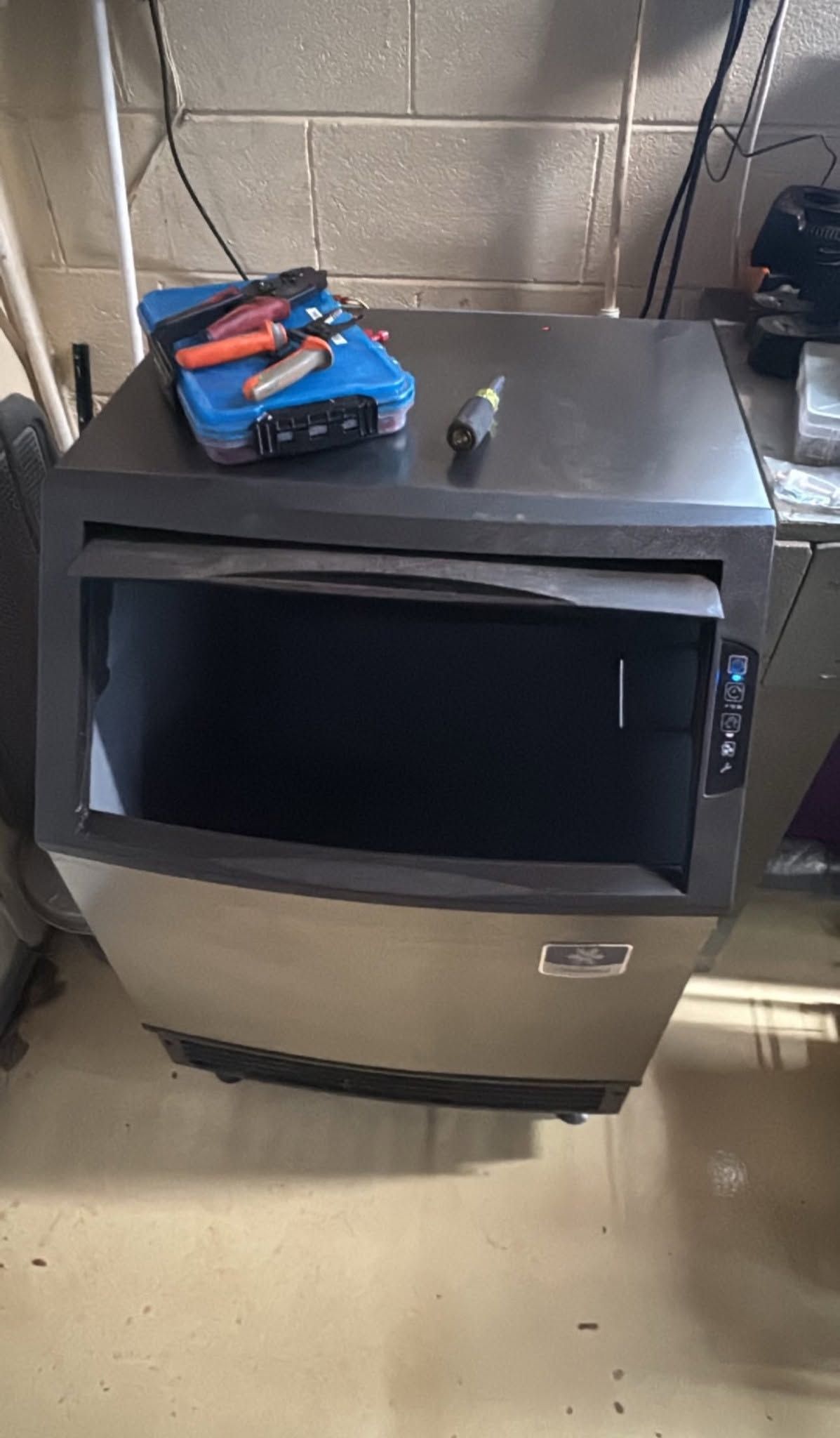 Black metal cabinet with open front and tools on top in a utility room