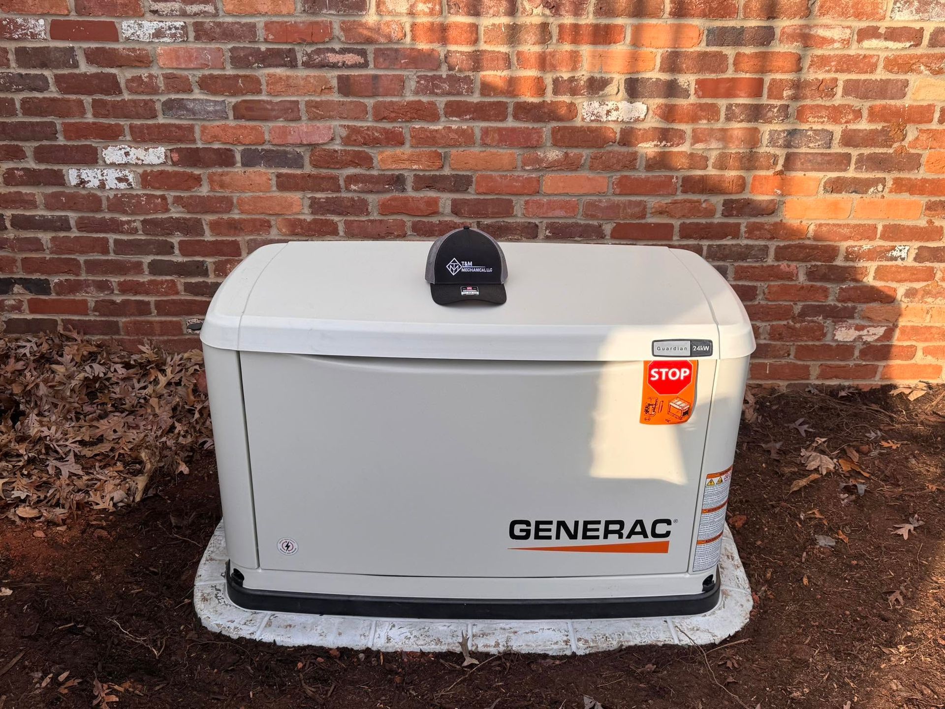 Gray Generac generator beside a brick wall with a red stop tag on top