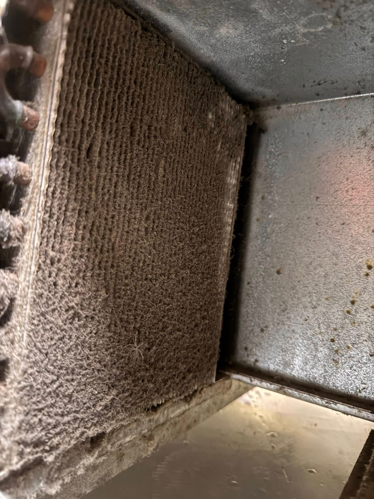 Dusty HVAC vent interior with a dirty brown filter and gray metal walls