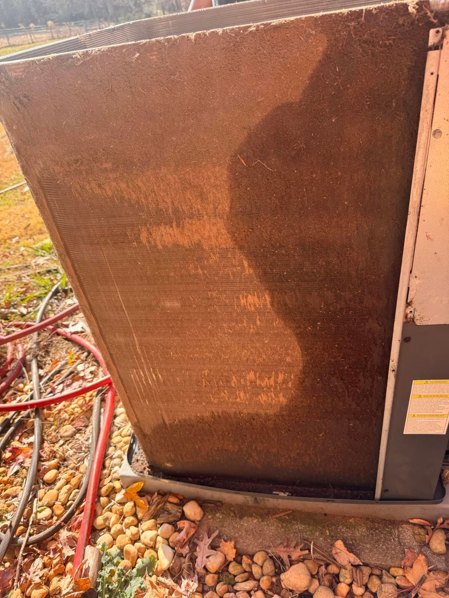 Rusty outdoor HVAC unit with red hoses and gravel on the ground