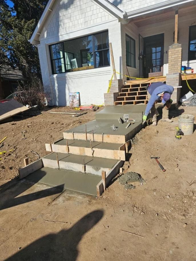 Construction worker pouring concrete steps leading to a house. 