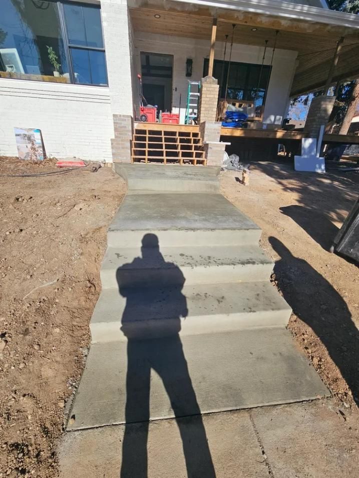 Concrete steps leading up to a building entrance; a person's shadow is cast on the steps.