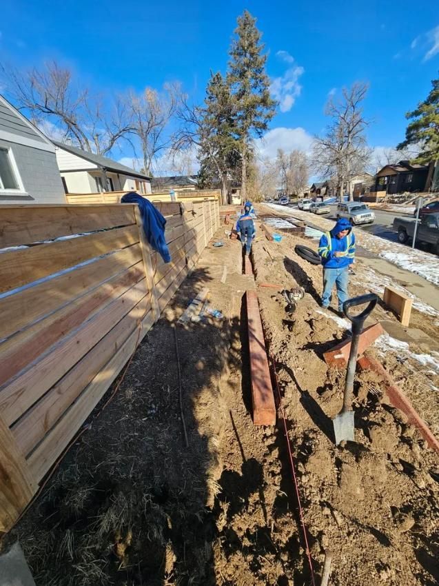 Construction site with workers building a fence and retaining wall. 