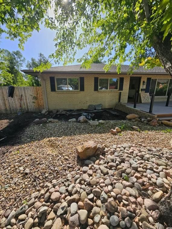 A house with a rock garden and fence on a sunny day.