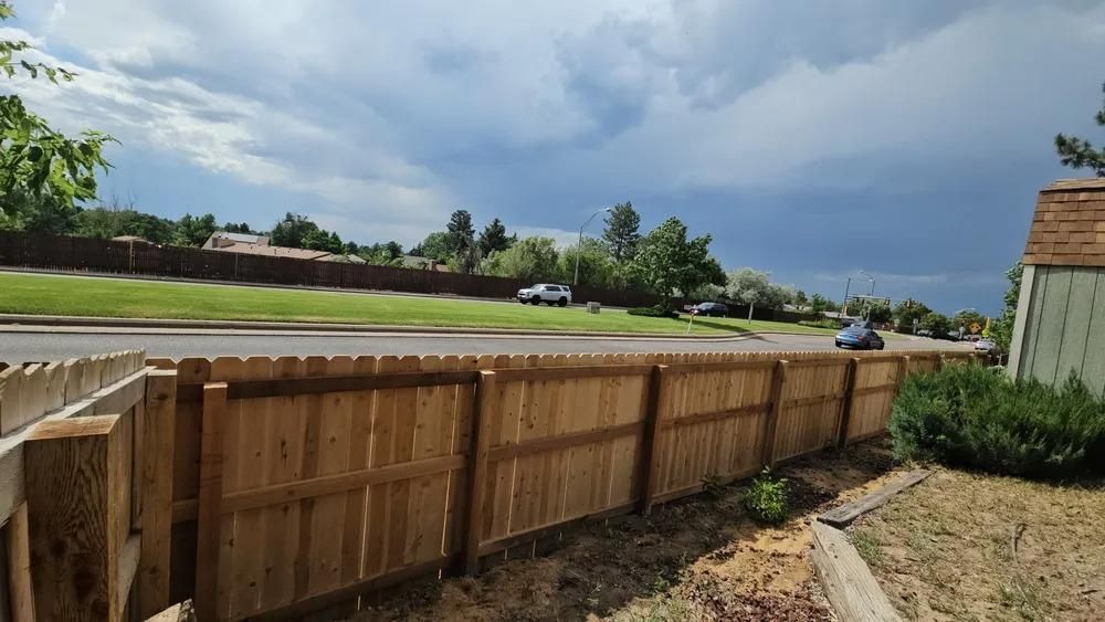 Wooden fence in front of a road with a car. 