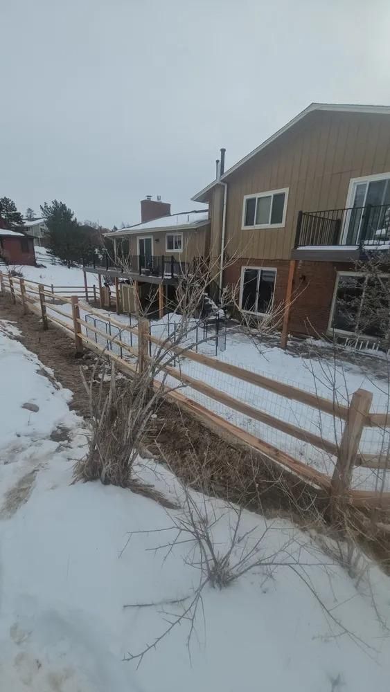 Snowy residential area with a wooden fence and multi-story buildings.