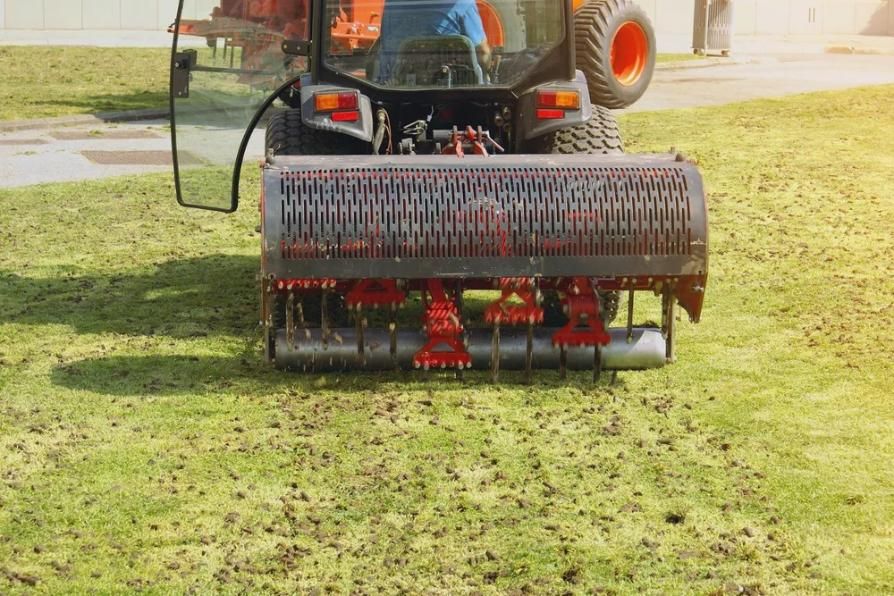 Tractor aerating lawn, with rotating spikes and visible plugs of soil.
