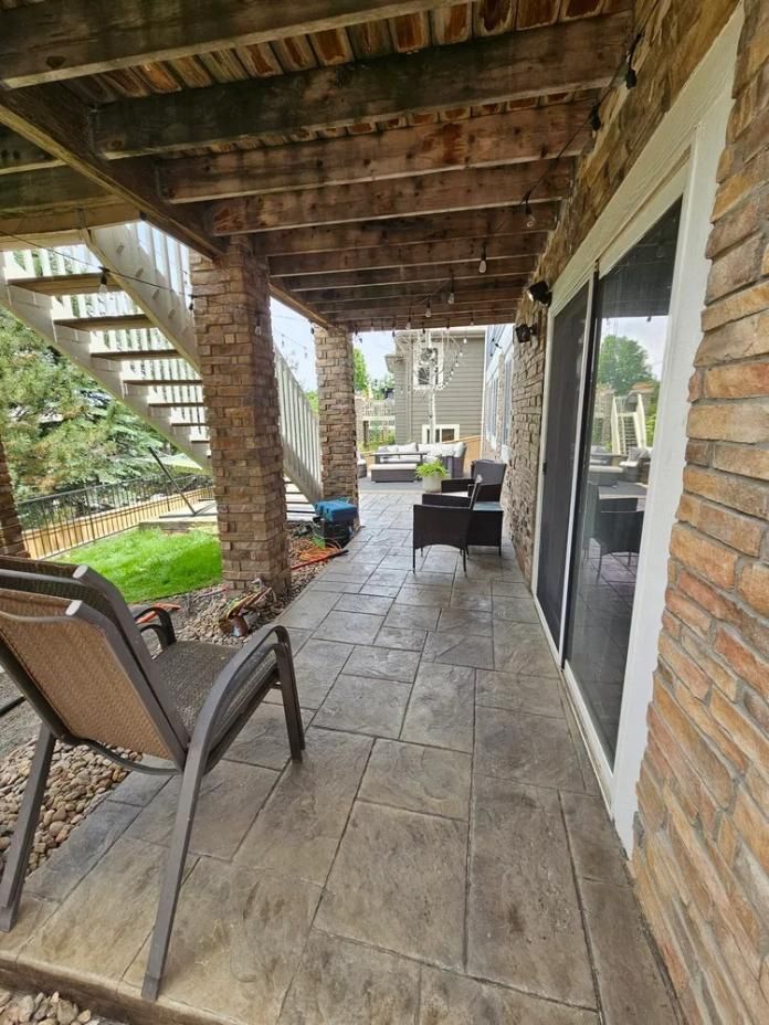 Patio under a deck with stone columns and stamped concrete flooring. 