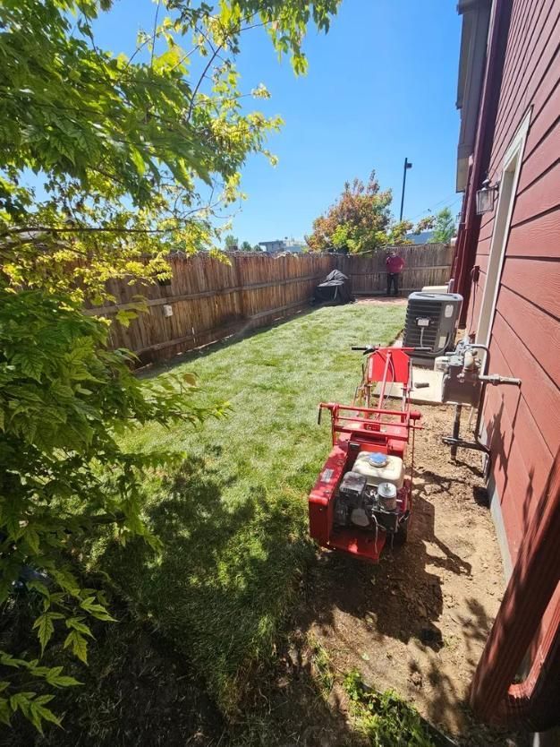 Lawn being edged near a red-sided building. 