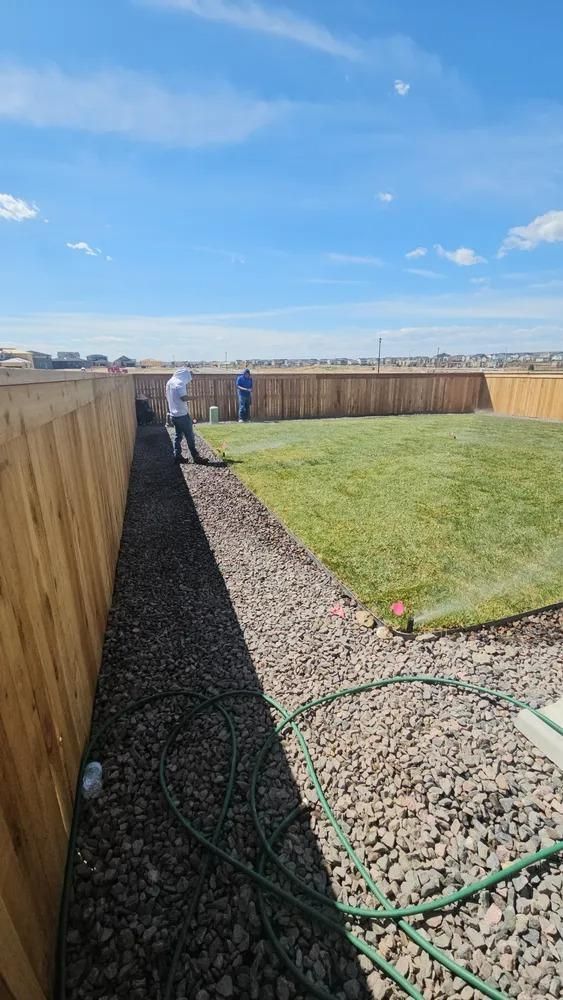 Backyard with gravel path, wooden fence, green lawn.