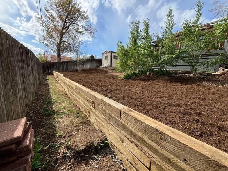 Wooden retaining wall along a mulched backyard. 