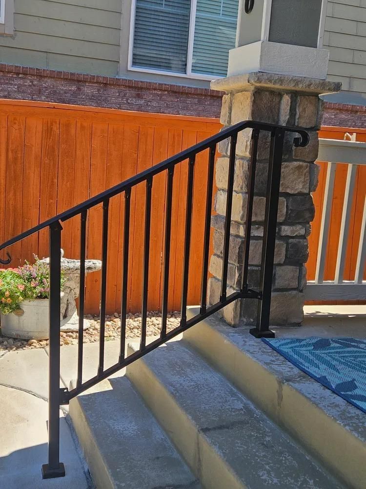 Black metal handrail on outdoor concrete steps.