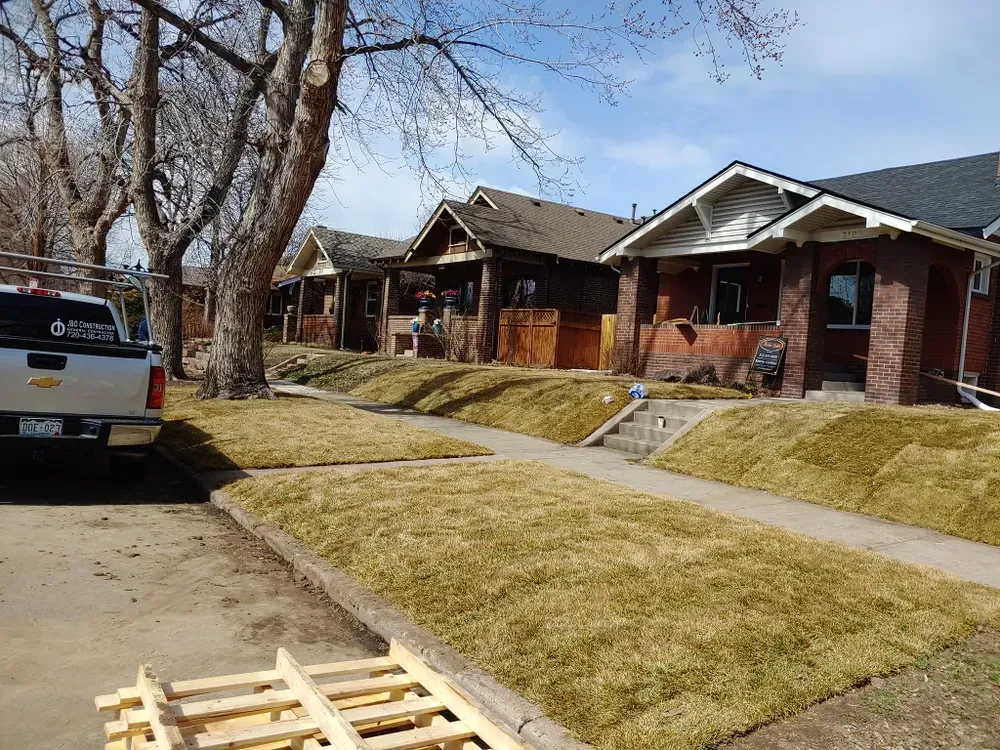 Houses with new sod in front yards; parked truck and street in foreground; blue sky.