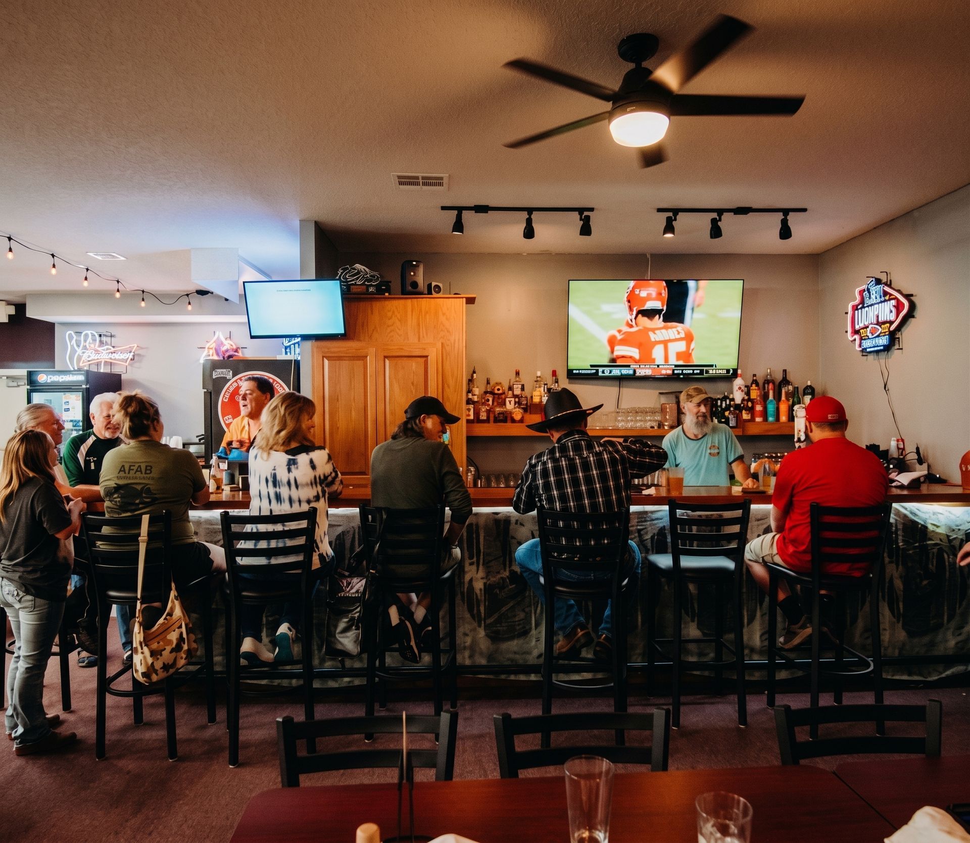 People seated at a bar watching a football game on TV in a sports bar.