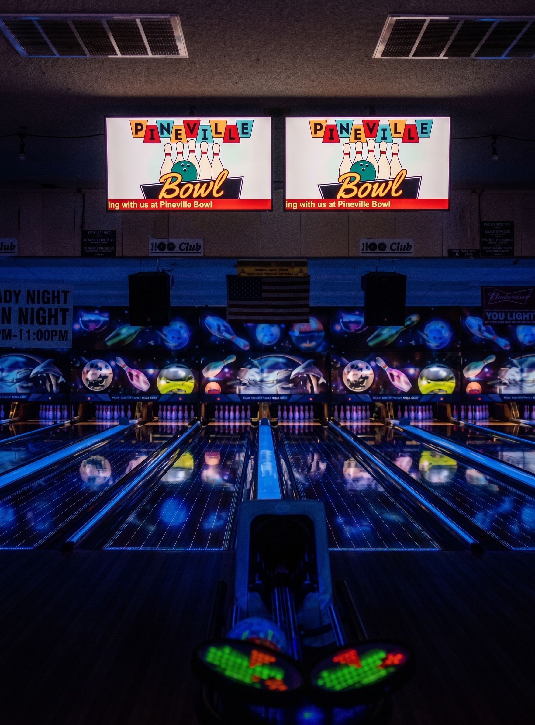 Neon-lit bowling alley with glowing lanes and two score screens overhead