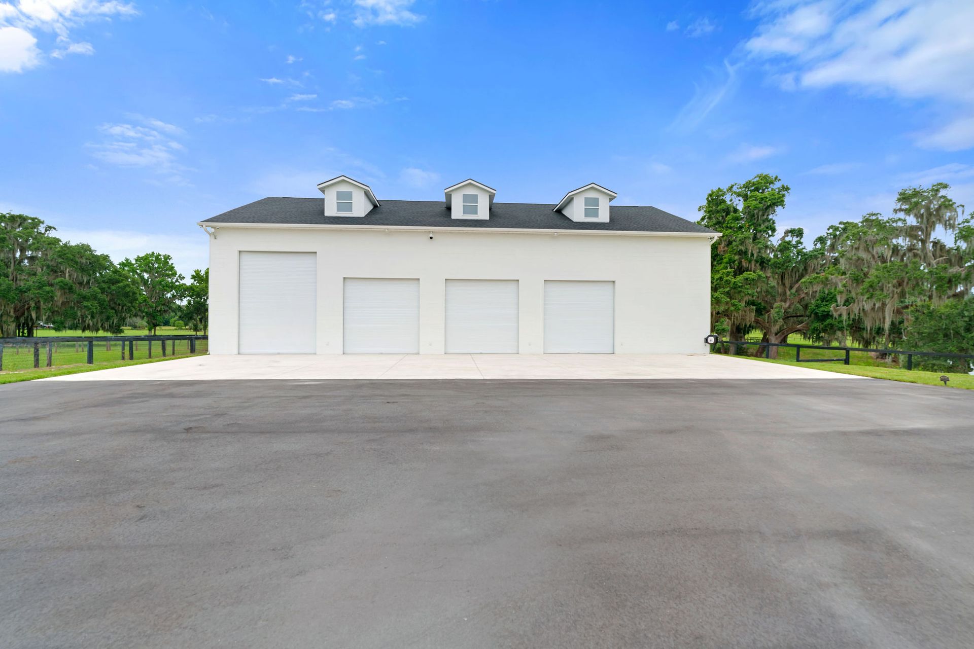 A white garage with three garage doors and a black roof