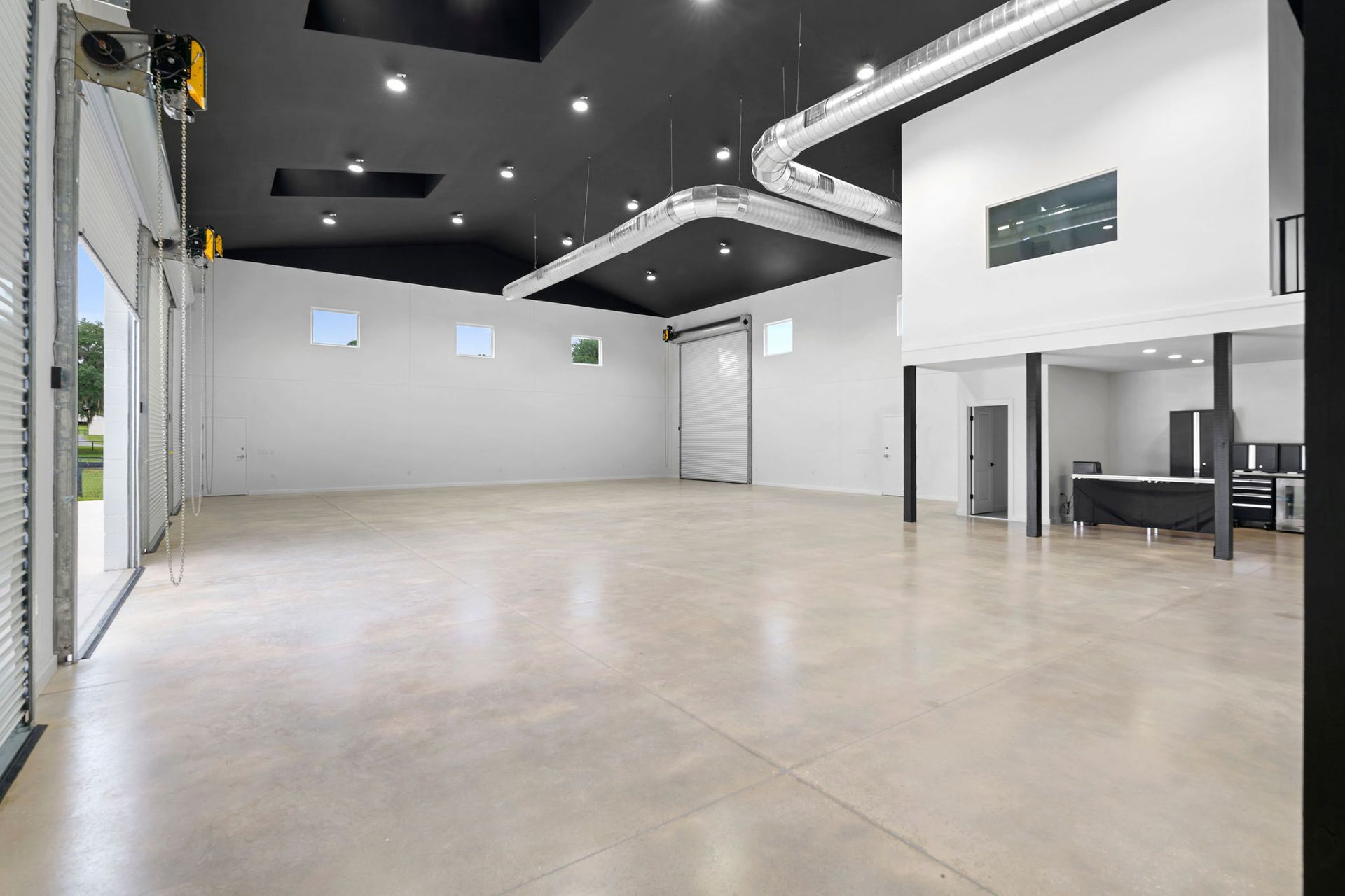 A large empty room with a concrete floor and a black ceiling.